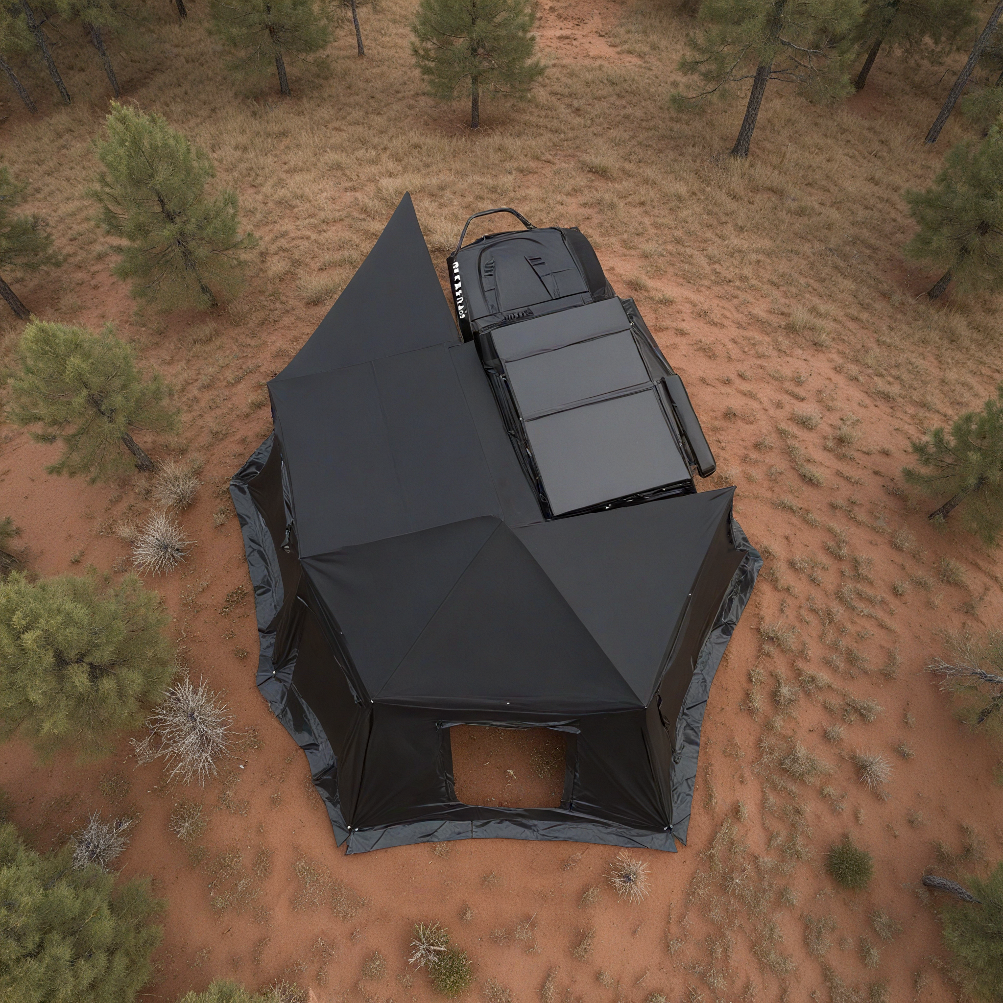 Aerial view of the OpenRoad 270 Awning Plus with its annex room attachment fully deployed over red desert soil, showing black waterproof canopy and side walls