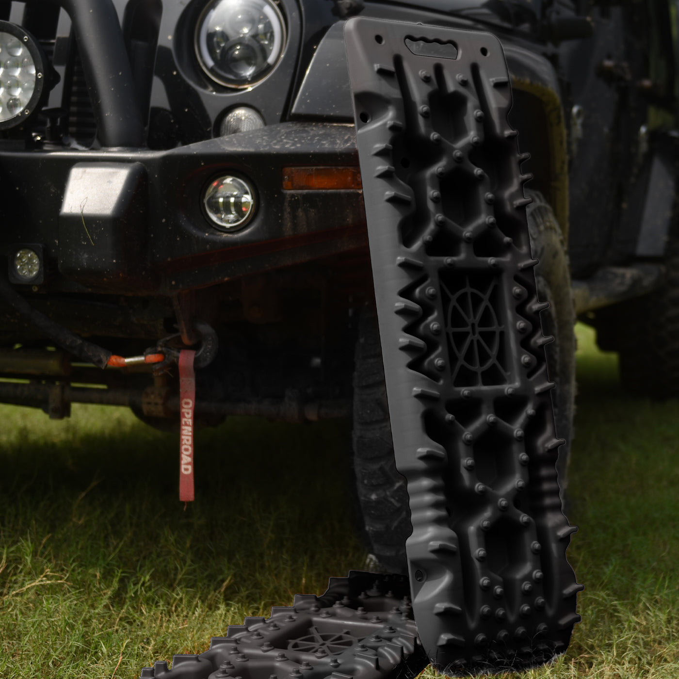 Openroad recovery tracks positioned beside a 4WD off-road vehicle, ideal for vehicle recovery in mud, sand, or grass terrain