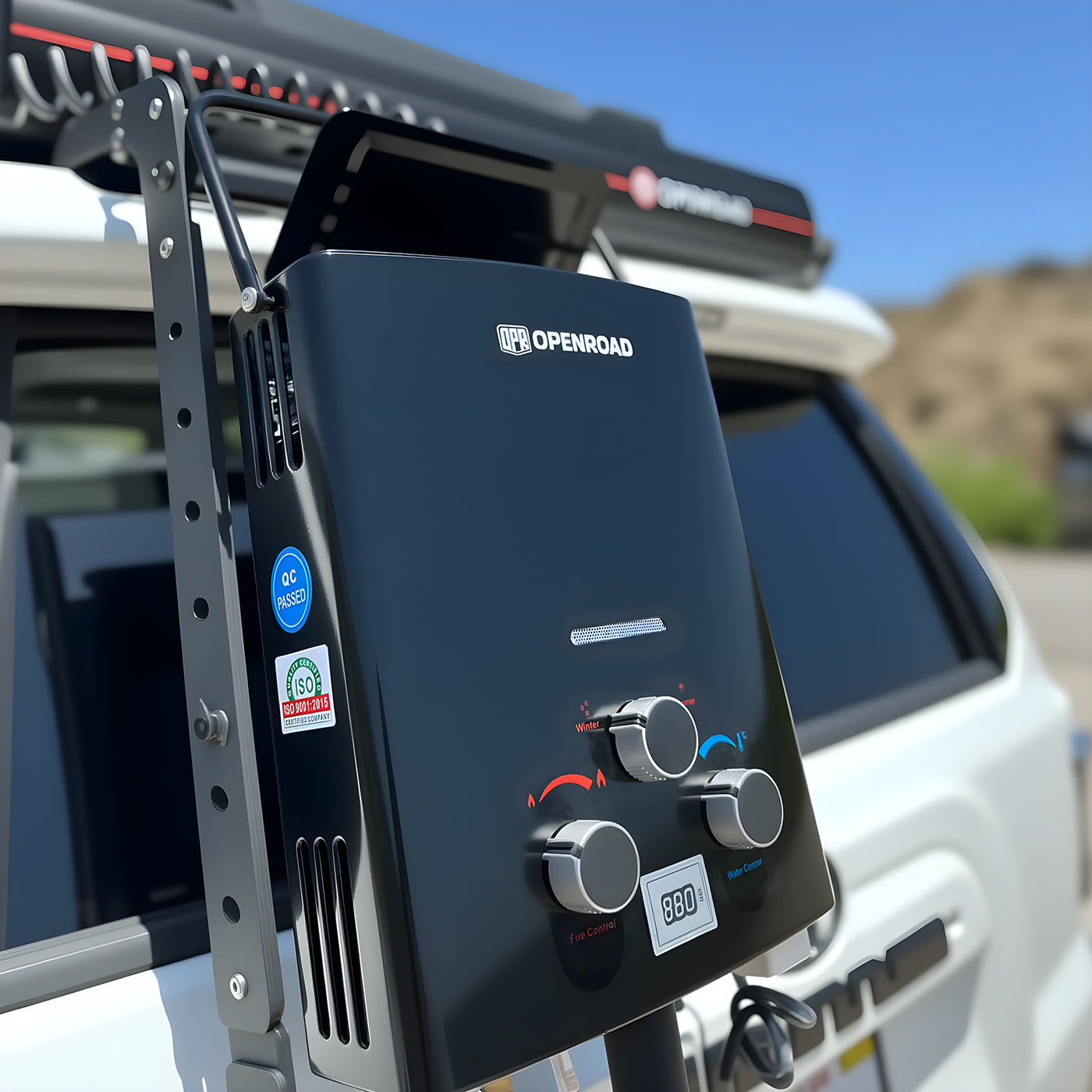 Close-up of OpenRoad portable camping hot water system mounted on 4WD ladder with visible control knobs and temperature display