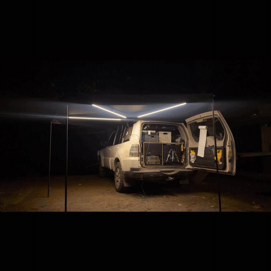OPENROAD 270 car awning with integrated LED strips (white mode) illuminating a night tailgate camping setup behind an SUV.