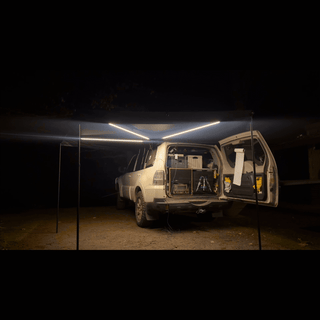OPENROAD 270 car awning with integrated LED strips (white mode) illuminating a night tailgate camping setup behind an SUV.
