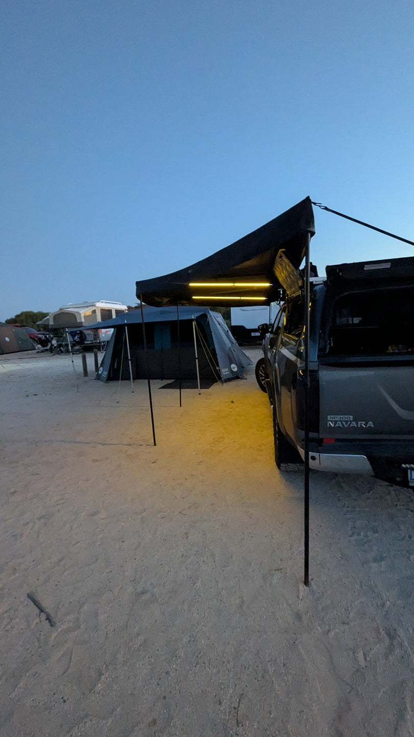 Openroad 270 awning set up on a Nissan Navara NP300 at night, providing wide shade and LED lighting for beach camping