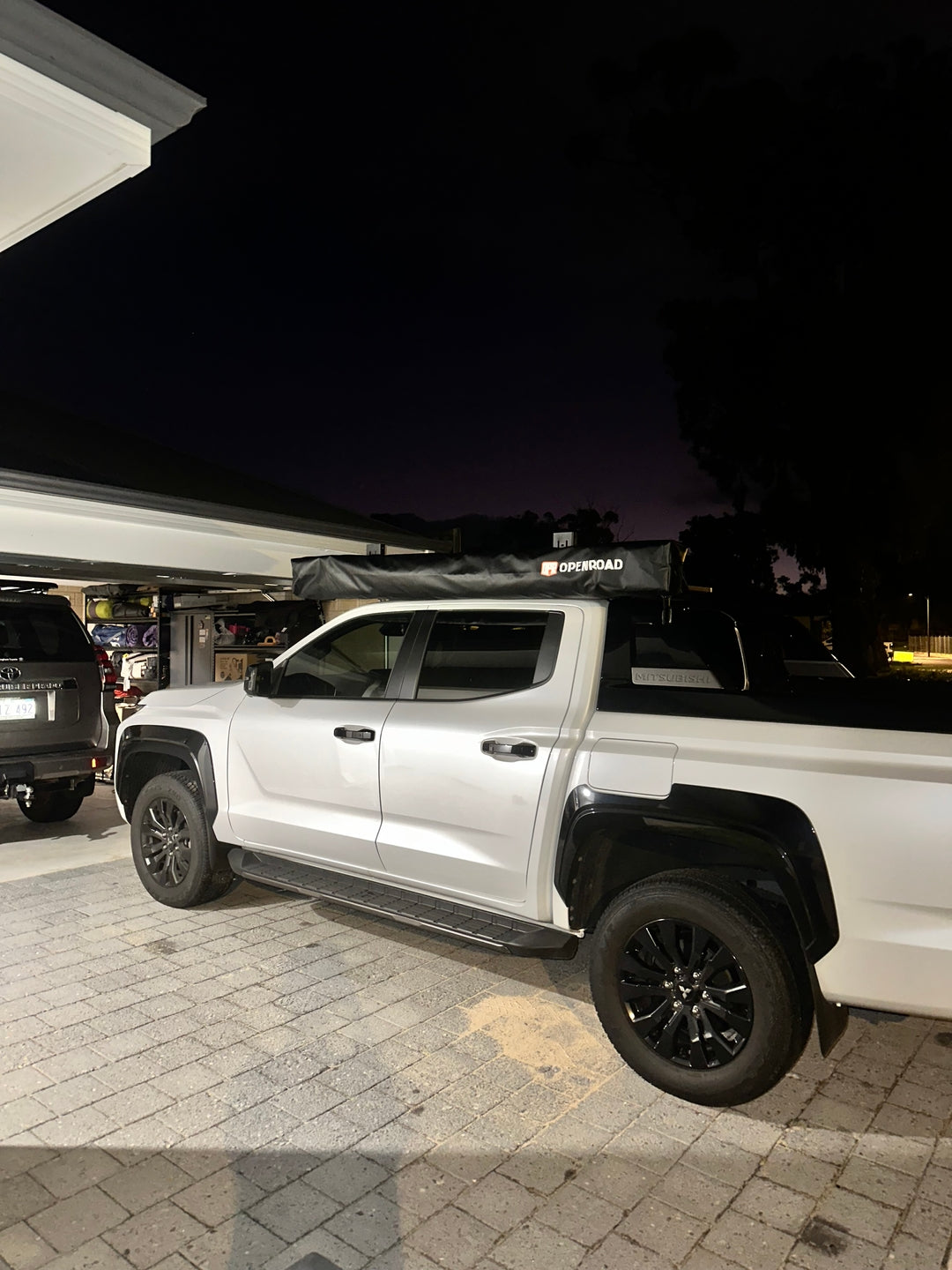 Side view of a Toyota Tacoma using an Openroad side awning mounted on the roof rack, creating practical shelter for camping at night